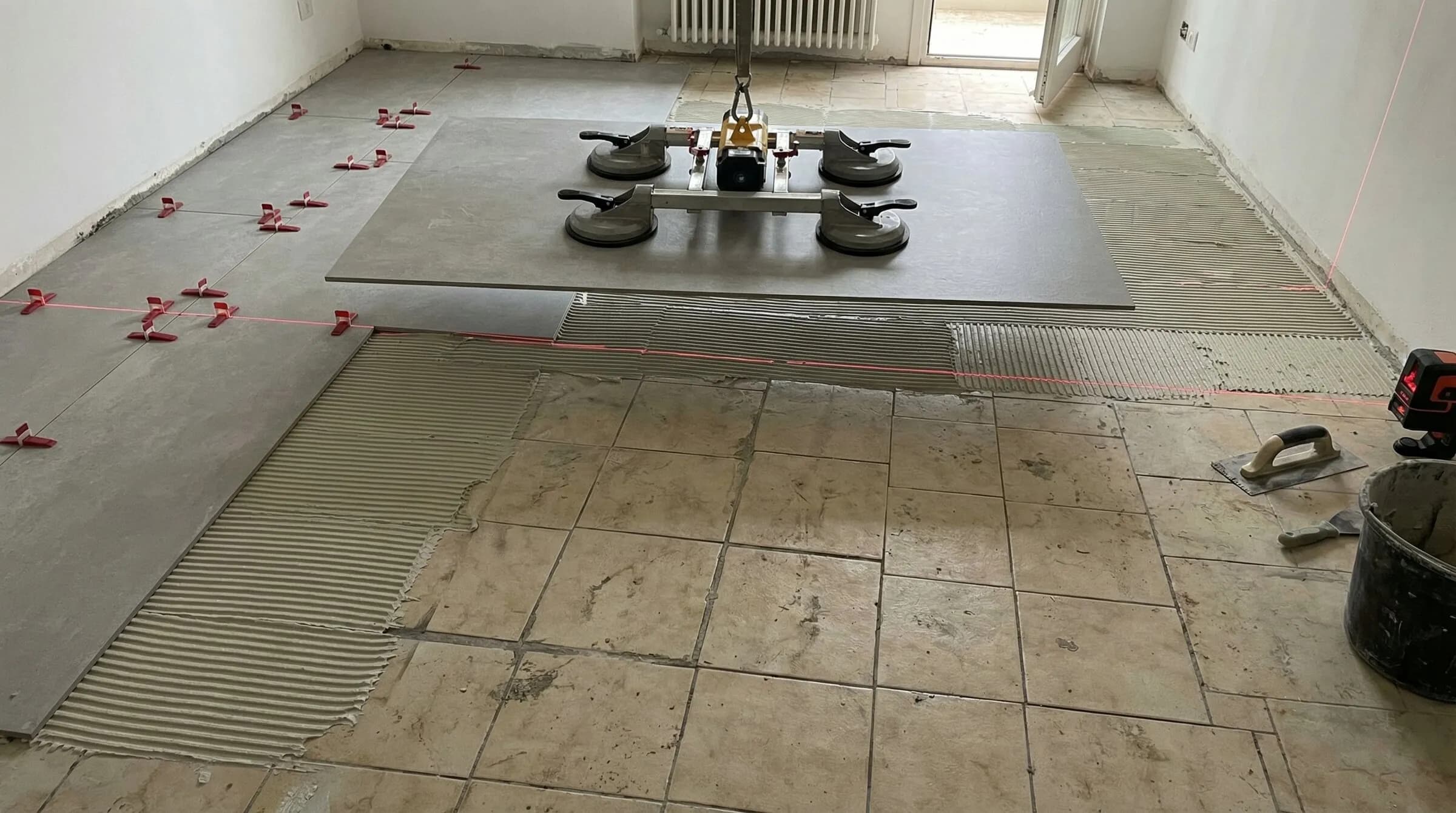 專業施工人員使用大型吸盤搬運 120x260cm 大板薄板,準備於舊有地磚上進行覆蓋施工